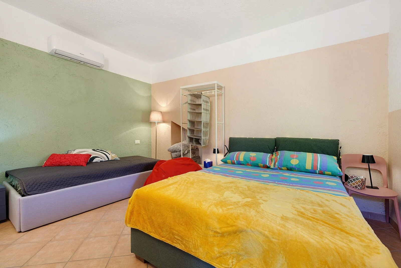 Camera Azzurra: letto matrimoniale con coperta gialla, testiera verde e biancheria colorata